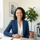 A smiling, diverse woman in a bright, modern home office setting representing a satisfied customer.